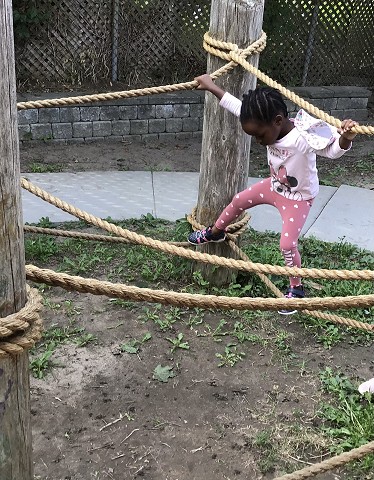 a child is playing on some ropes
